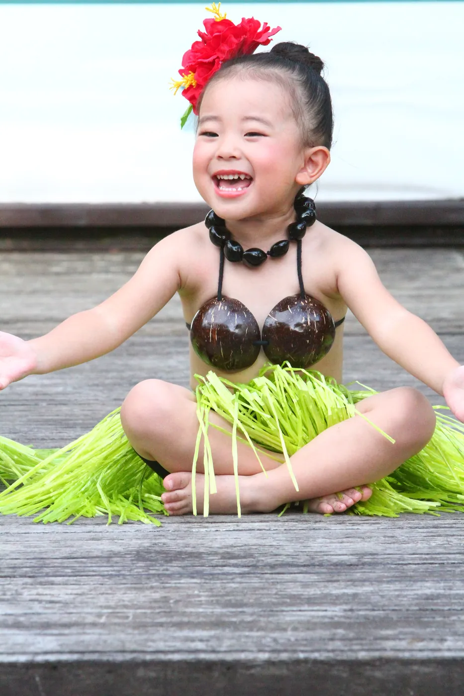 ココナッツの衣装で笑顔の小さなフラダンサー